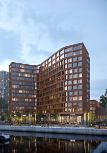 3D render of a curved red-brick residential building along a waterfront with ground-floor retail, shown at dusk